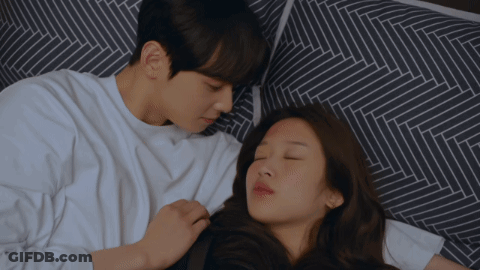 A Man And A Woman Are Laying On A Bed Together GIF