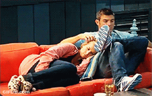 A Man And A Woman Are Laying On A Couch GIF