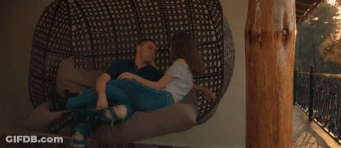 A Man And A Woman Are Laying On A Couch With The Sun Shining Through Them GIF