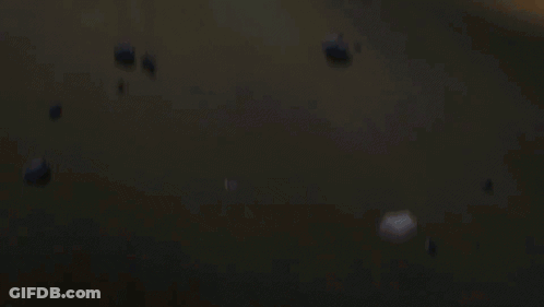 A Man And A Woman Are Laying On The Ground With A Fire Behind Them GIF