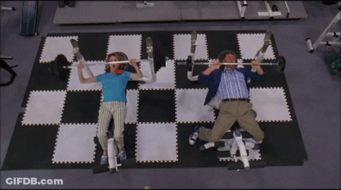 A Man And A Woman Are Lifting Weights On A Checkered Floor GIF