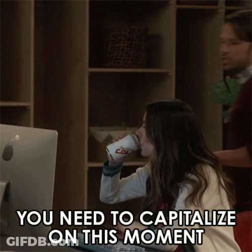 A Man And A Woman Are Looking At A Computer Screen With The Words You Need To Capitalize On This Moment GIF