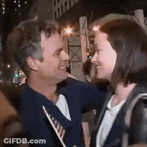 A Man And A Woman Are Looking At Each Other And Smiling . GIF