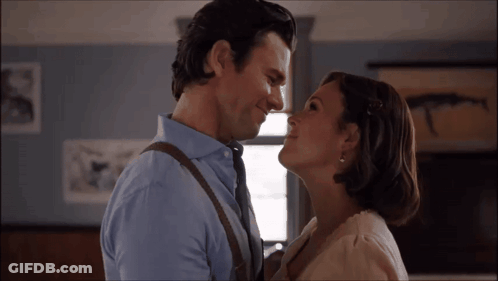 A Man And A Woman Are Looking At Each Other And Smiling GIF