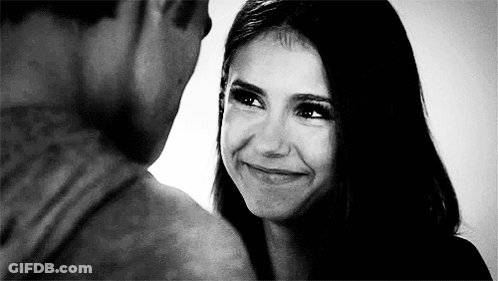 A Man And A Woman Are Looking At Each Other And Smiling . GIF