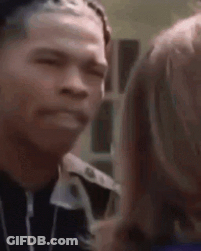 A Man And A Woman Are Looking At Each Other And The Man Is Making A Face . GIF