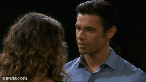 A Man And A Woman Are Looking At Each Other And The Man Is Wearing A Blue Shirt GIF