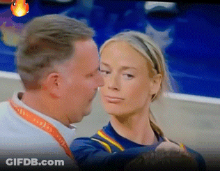 A Man And A Woman Are Looking At Each Other And The Man Is Wearing A Lanyard That Says ' A ' GIF