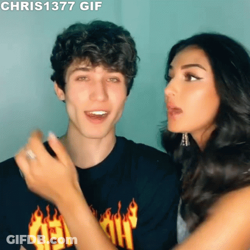 A Man And A Woman Are Looking At Each Other And The Man Is Wearing A Shirt With Flames On It GIF