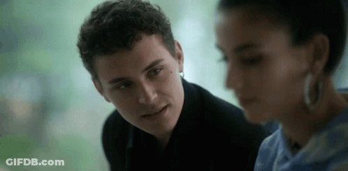A Man And A Woman Are Looking At Each Other And The Man Is Wearing Earrings . GIF