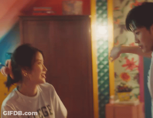 A Man And A Woman Are Looking At Each Other And The Woman Is Wearing A T-Shirt That Says College GIF