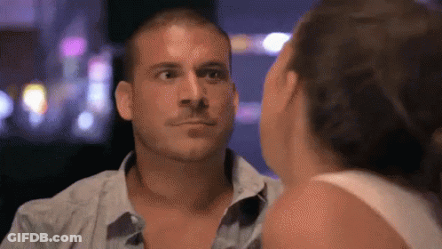 A Man And A Woman Are Looking At Each Other In A Dark Room GIF