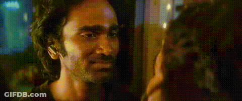 A Man And A Woman Are Looking At Each Other In A Dark Room . GIF