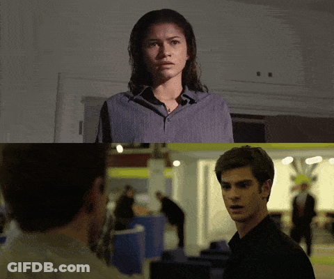 A Man And A Woman Are Looking At Each Other In A Dark Room GIF