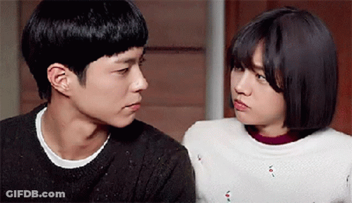 A Man And A Woman Are Looking At Each Other In A Room . GIF
