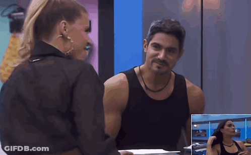 A Man And A Woman Are Looking At Each Other In Front Of A Mirror GIF