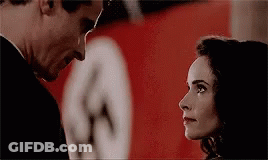 A Man And A Woman Are Looking At Each Other In Front Of A Nazi Flag . GIF