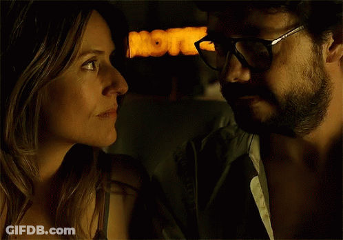 A Man And A Woman Are Looking At Each Other In Front Of A Sign That Says Motel GIF