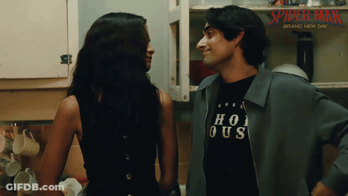A Man And A Woman Are Looking At Each Other In Front Of A Sign That Says Spider-Man Brand New Day GIF