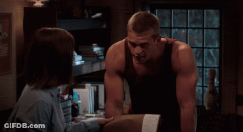 A Man And A Woman Are Looking At Each Other In Front Of A Texas Poster GIF