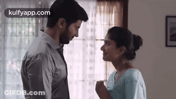 A Man And A Woman Are Looking At Each Other In Front Of A Window . GIF