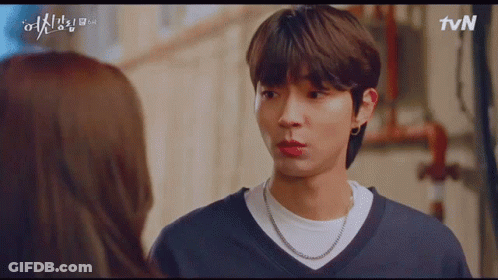 A Man And A Woman Are Looking At Each Other . The Man Is Wearing A Necklace . GIF