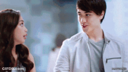A Man And A Woman Are Looking At Each Other . The Man Is Wearing A White Jacket . GIF