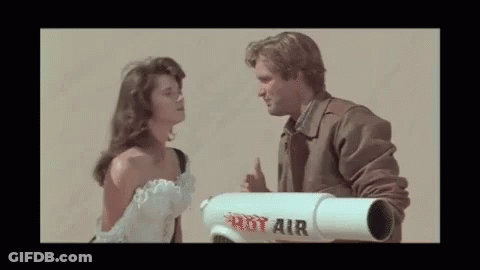 A Man And A Woman Are Looking At Each Other While A Man Holds A Rot Air Rocket . GIF