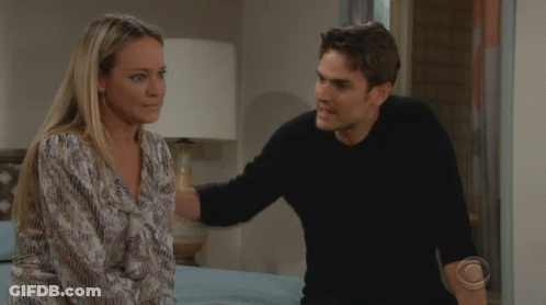 A Man And A Woman Are Looking At Each Other With A Cbs Logo On The Bottom Left GIF