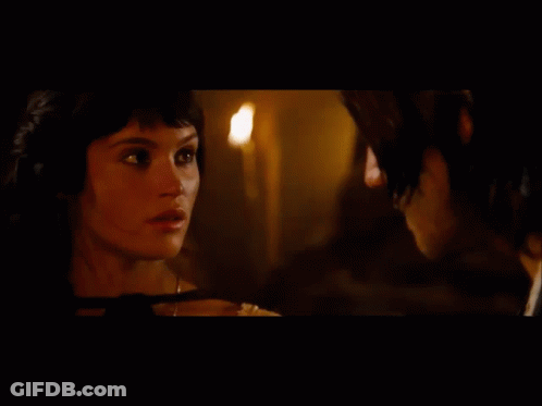 A Man And A Woman Are Looking At Each Other With A Mountain In The Background GIF