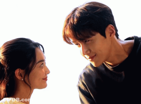 A Man And A Woman Are Looking At Each Other With A White Background GIF