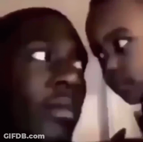 A Man And A Woman Are Looking At Each Other With Their Eyes Wide Open . GIF