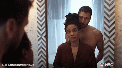 A Man And A Woman Are Looking At Themselves In A Mirror With The Hashtag #Newamsterdam On The Bottom GIF