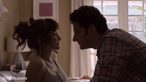 A Man And A Woman Are Looking Into Each Other 'S Eyes In A Bedroom GIF