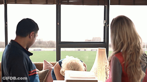A Man And A Woman Are Looking Out Of A Window GIF