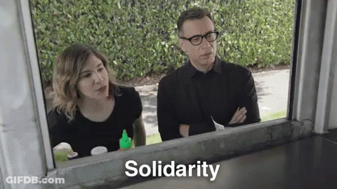 A Man And A Woman Are Looking Out Of A Window And The Word Solidarity Is Written On The Window . GIF