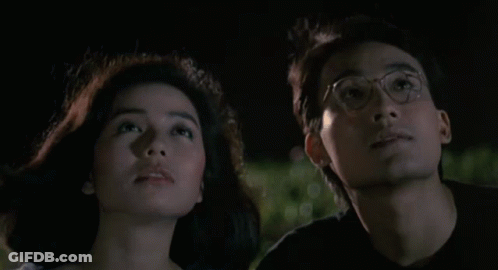 A Man And A Woman Are Looking Up At The Sky Together GIF
