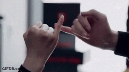 A Man And A Woman Are Making A Pinkie Promise With Their Fingers . GIF