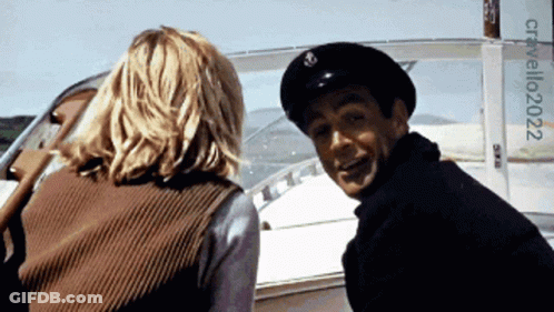 A Man And A Woman Are On A Boat With A Sign That Says Cristallo2022 On It GIF