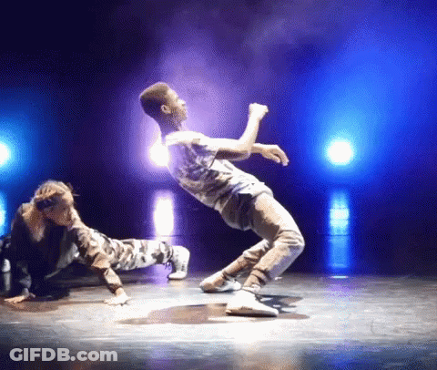 A Man And A Woman Are Performing On A Stage With Blue Lights Behind Them GIF