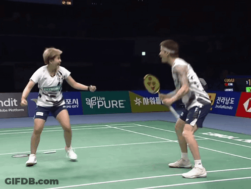 A Man And A Woman Are Playing A Game Of Badminton On A Court That Has A Banner That Says Pure GIF