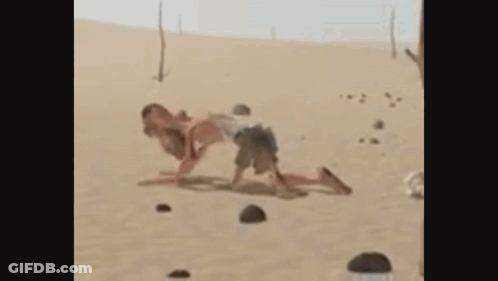A Man And A Woman Are Playing In The Sand . GIF