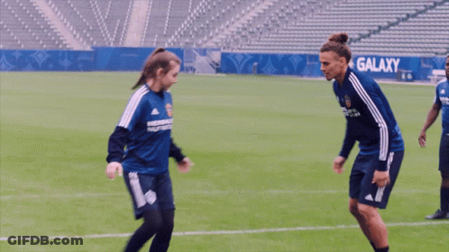 A Man And A Woman Are Playing Soccer And The Woman Is Wearing A Shirt That Says Herbalife On It GIF