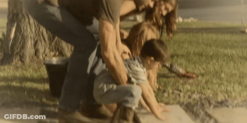 A Man And A Woman Are Playing With A Child On The Sidewalk GIF