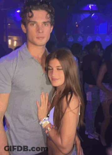 A Man And A Woman Are Posing For A Photo In A Club GIF