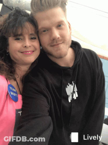 A Man And A Woman Are Posing For A Picture And The Man Is Wearing A Black Hoodie With The Word Scott On It GIF