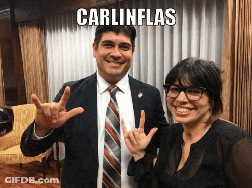 A Man And A Woman Are Posing For A Picture And The Man Is Wearing A Suit And Tie And The Woman Is Wearing Glasses GIF