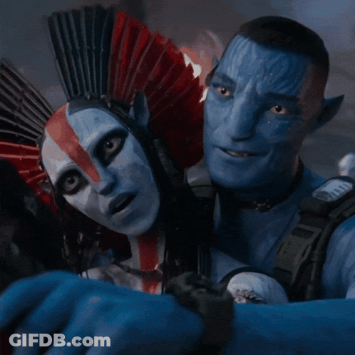 A Man And A Woman Are Posing For A Picture And The Woman Is Wearing A Red And White Headdress GIF