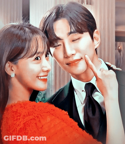 A Man And A Woman Are Posing For A Picture And The Woman Is Wearing A Red Dress GIF