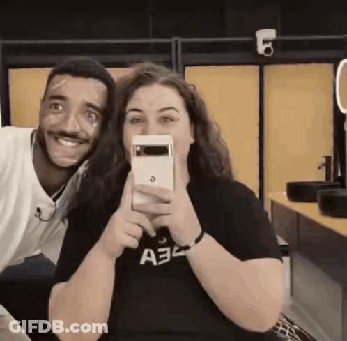 A Man And A Woman Are Posing For A Picture And The Woman Is Wearing A Shirt That Says A32 On It GIF
